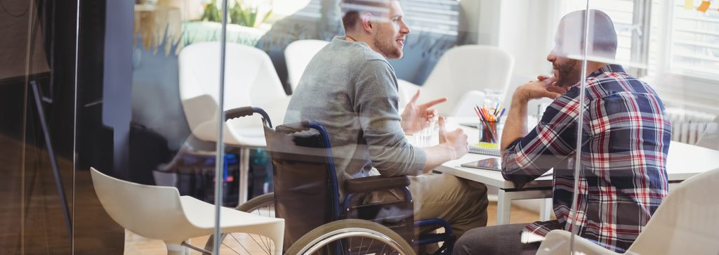 image: person with disability working with colleague in creative office